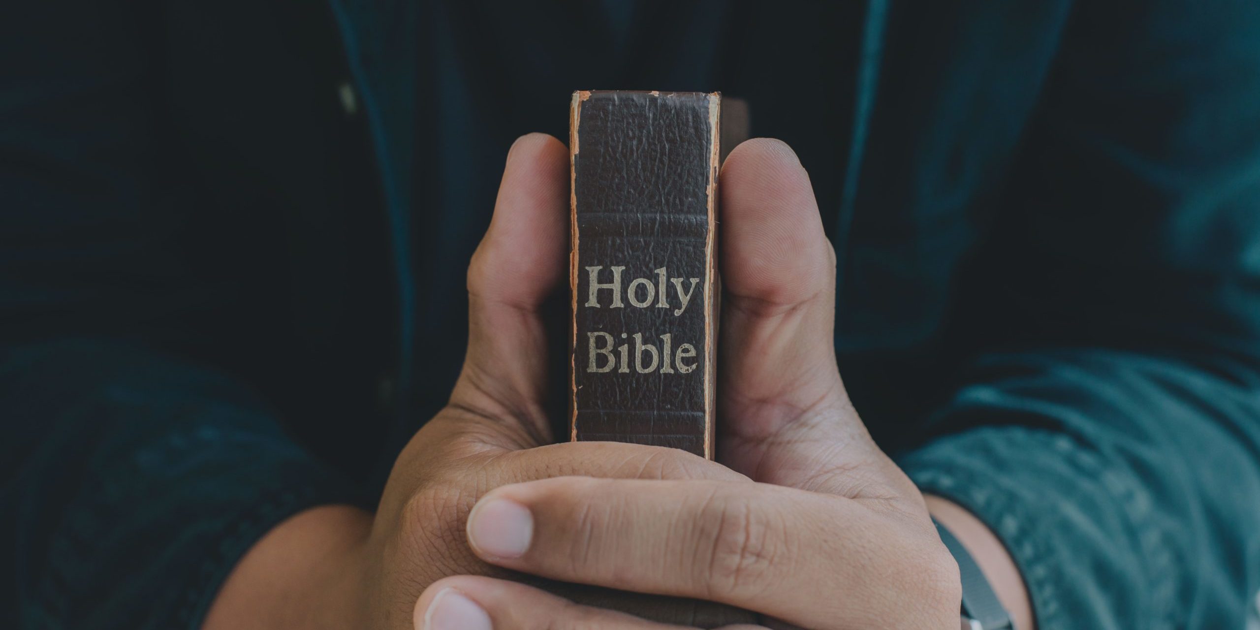 A Man praying holding a Holy Bible and praying in bed room. religion, praying, education and bible study. Christian concept.