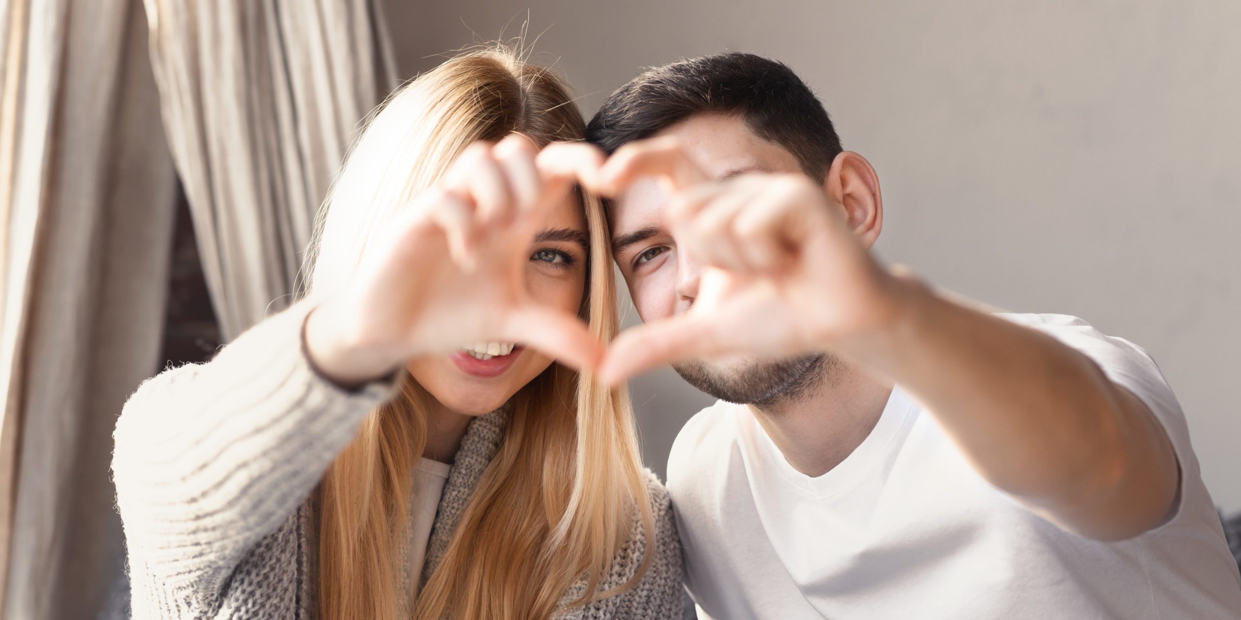 Romantic couple making heart with their hands at home