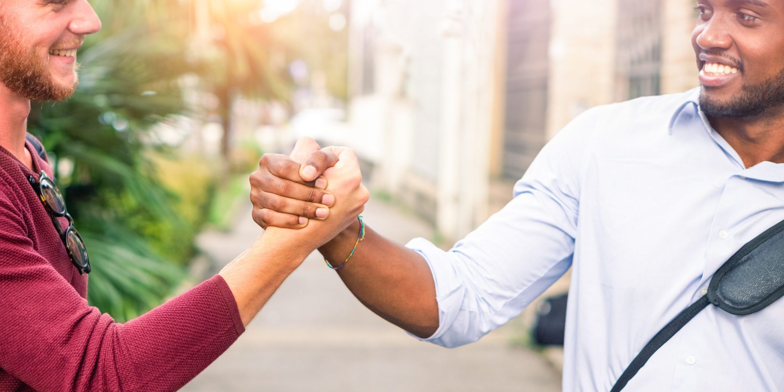 Interracial friends greating each other with handshaking in the street cropped image - Young business men friendly hands gesture outdoors - Concept of friendship and different people relations