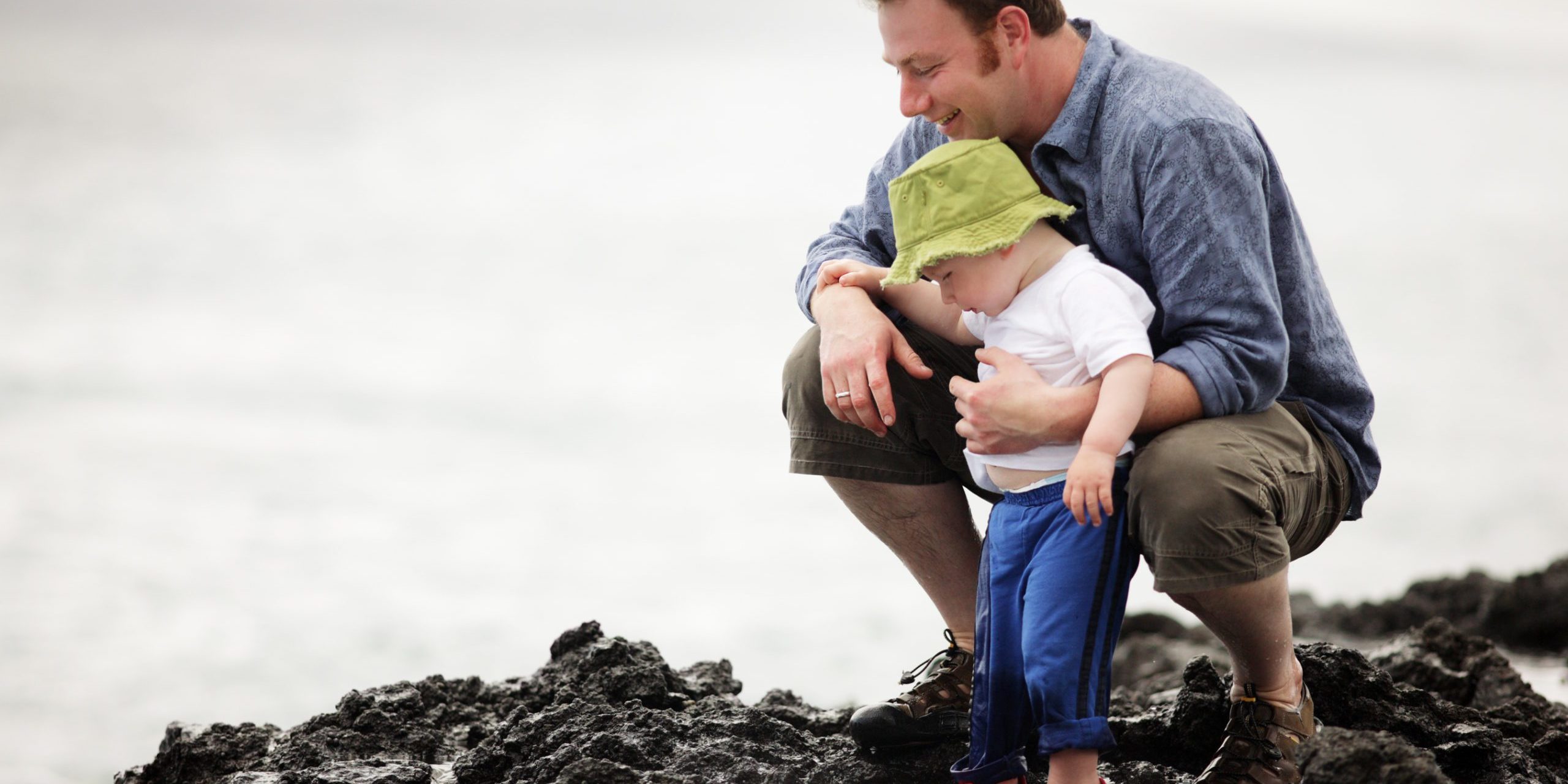 Young father with little son outdoors at ocean